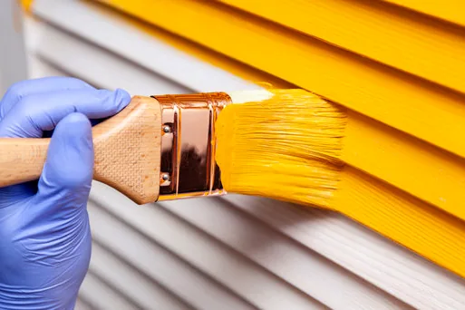 Brushing color onto shutters at a Lido Isle home