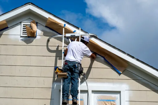 Painter masking windows on a coastal home before spraying